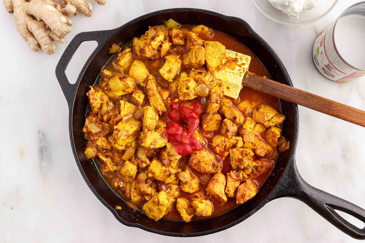 adding tomato paste to chicken curry