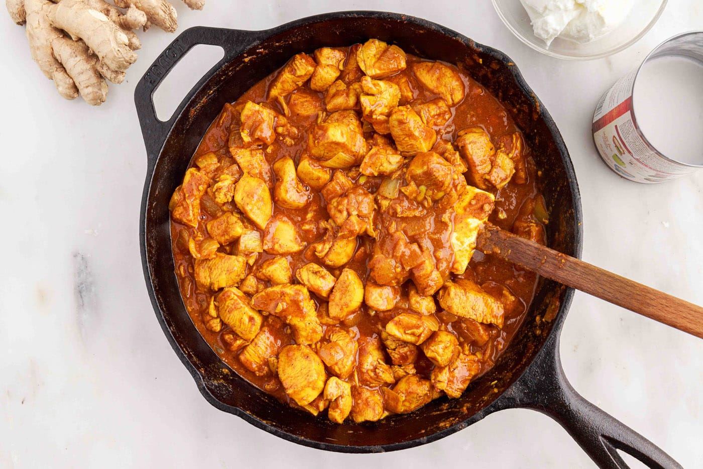 chicken curry in a skillet with a rubber spatula