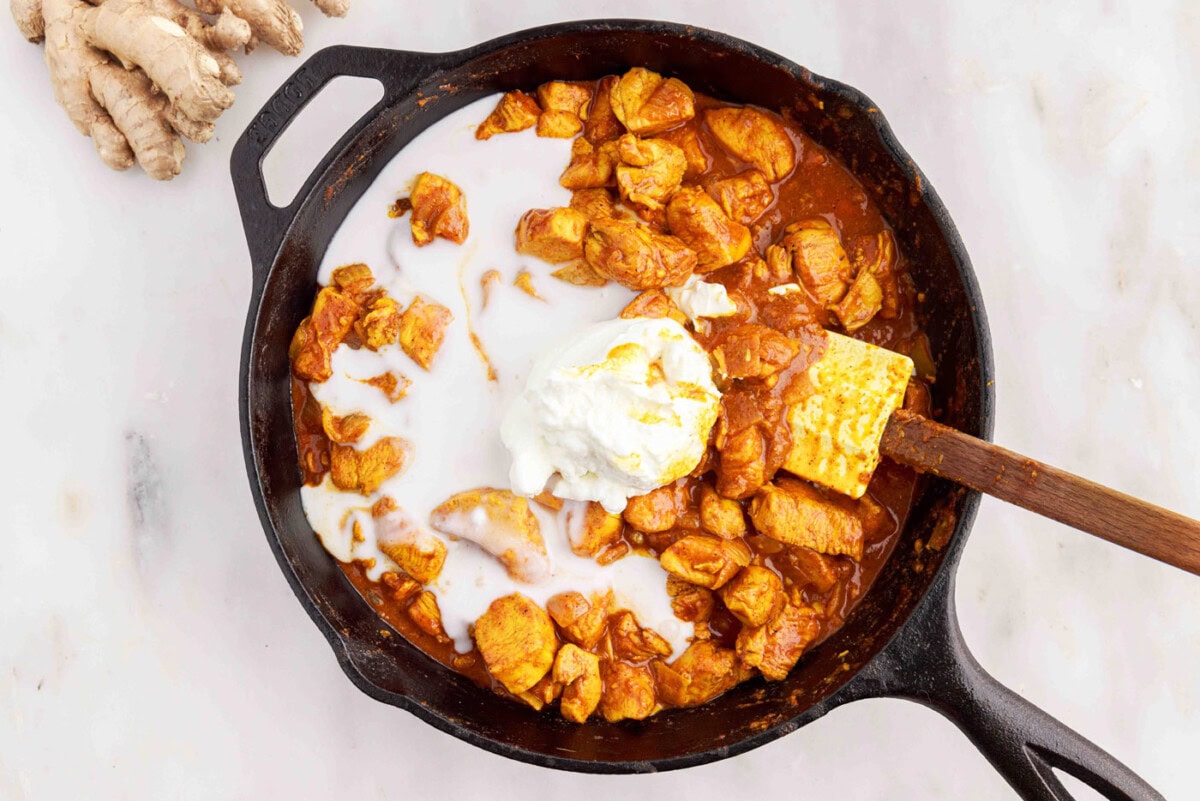 mixing coconut milk and yogurt into chicken curry
