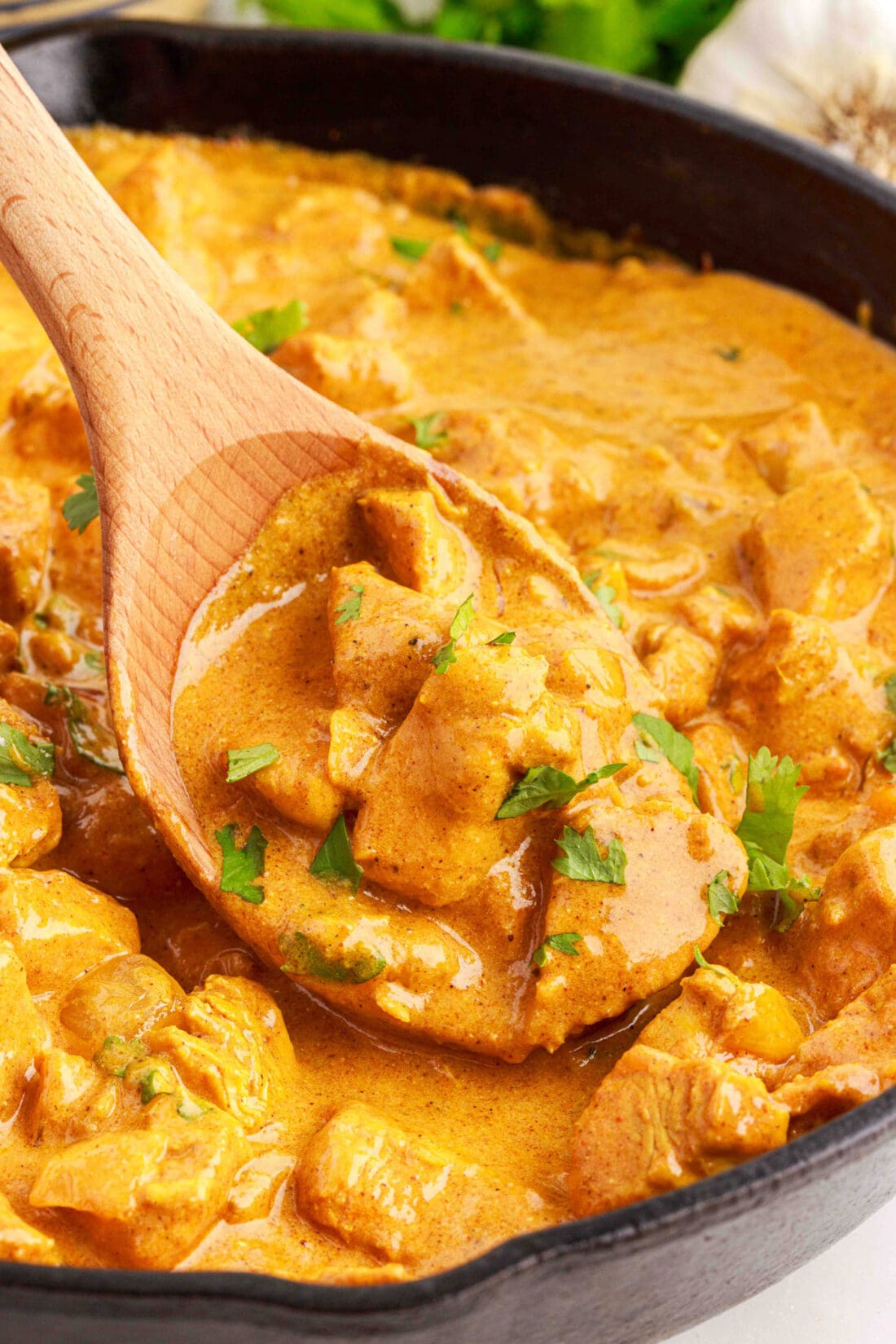Close up photo of a spoon of Chicken Curry in a skillet of Chicken Curry