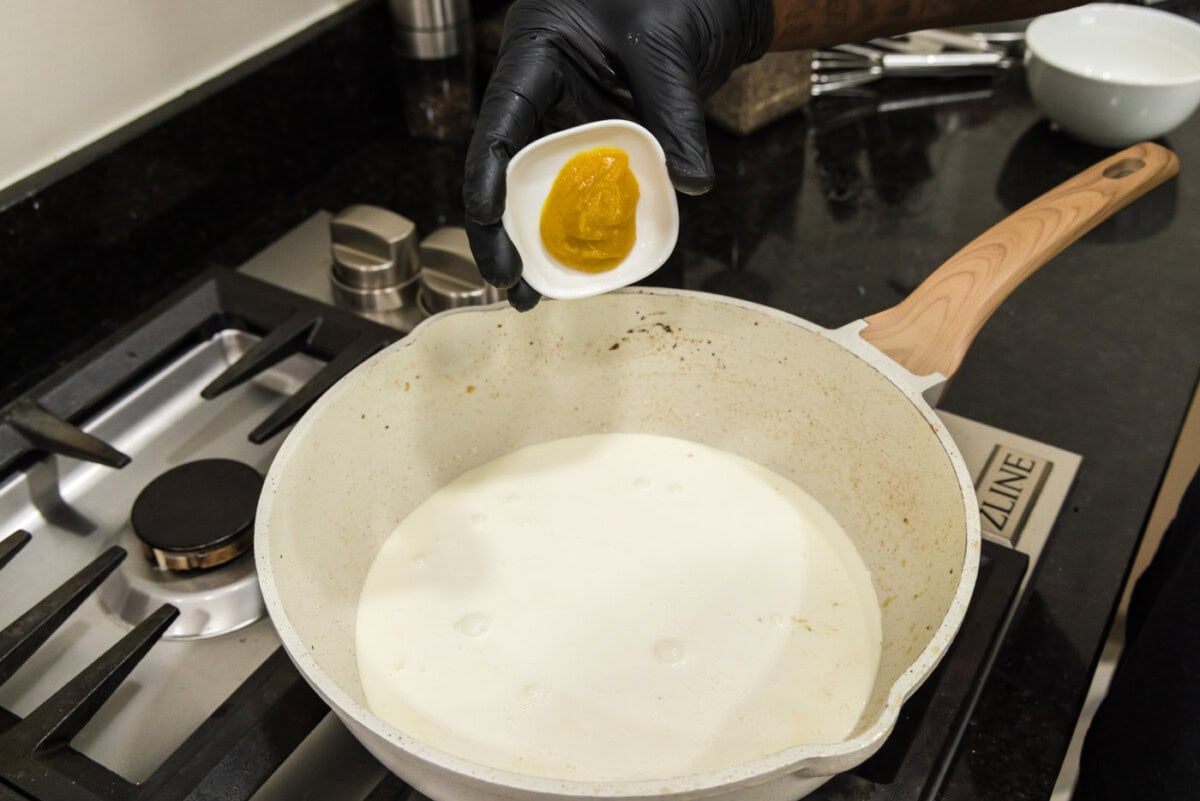 adding chicken base to skillet of heavy cream