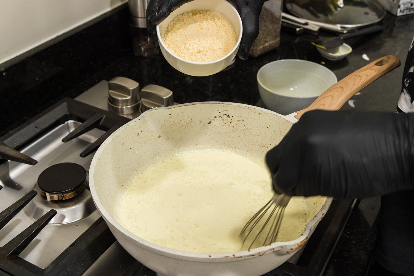 adding parmesan cheese to heavy cream and egg mixture in a skillet