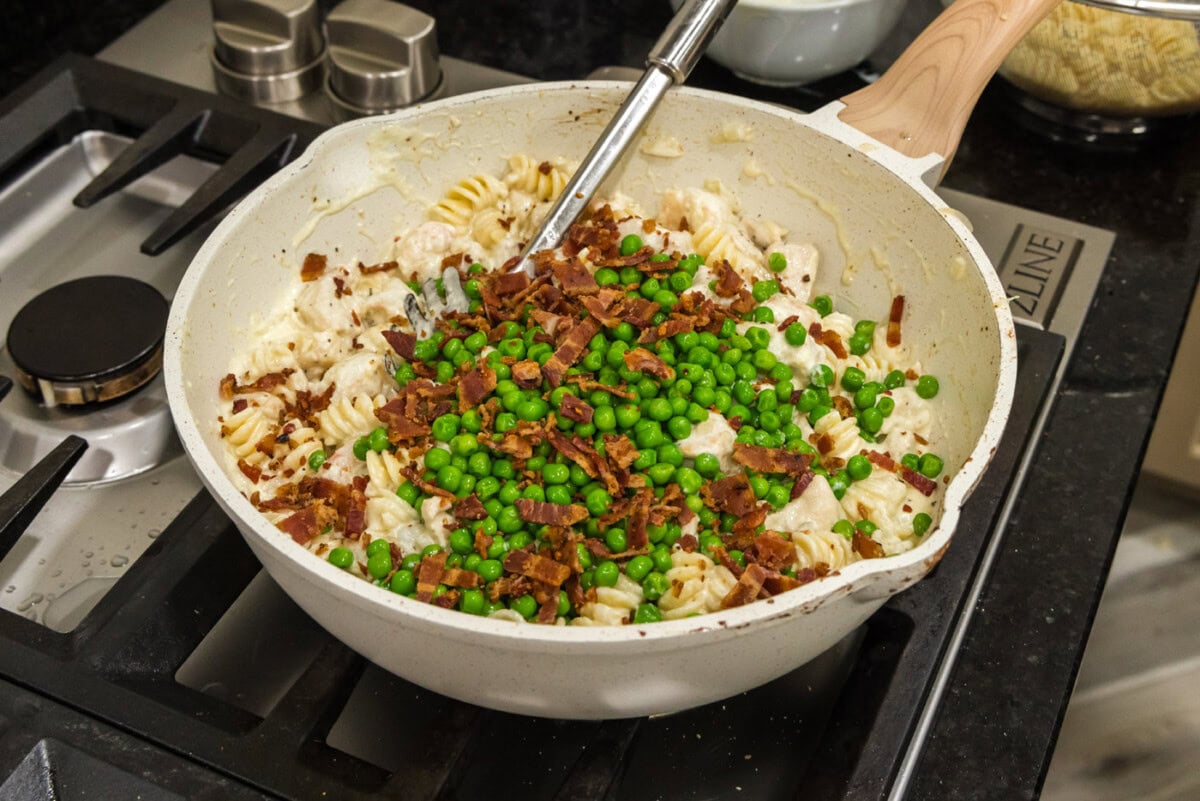 adding peas and bacon to chicken and shrimp carbonara