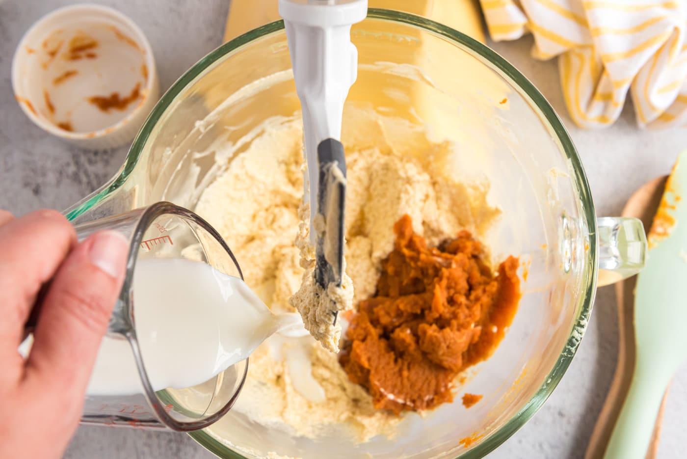 adding pumpkin puree and buttermilk to butter mixture in a bowl for muffins