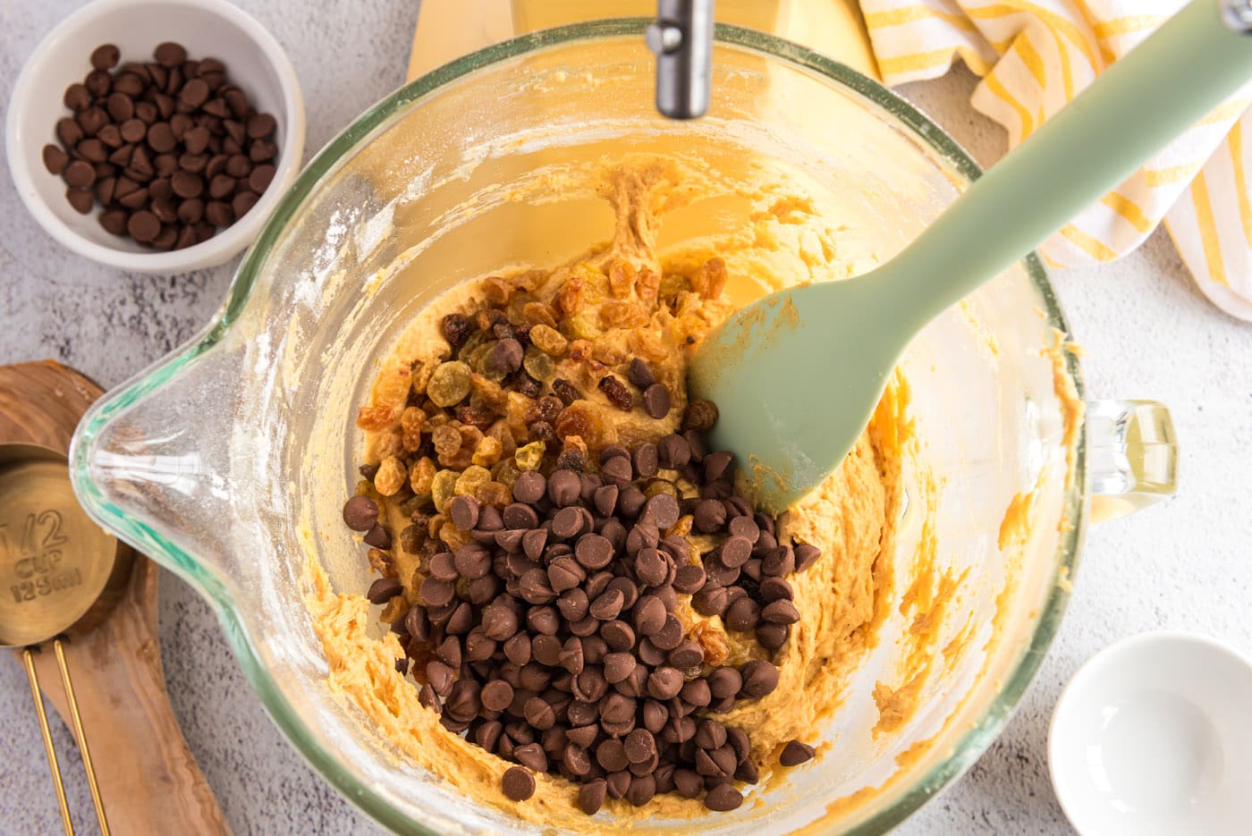 adding chocolate chips and raisins to pumpkin muffin batter