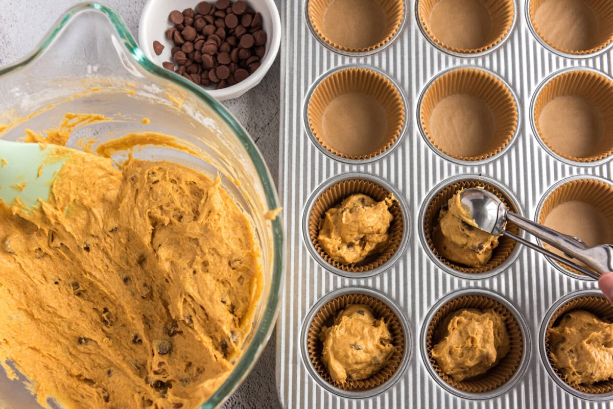 scooping pumpkin muffin dough into pan