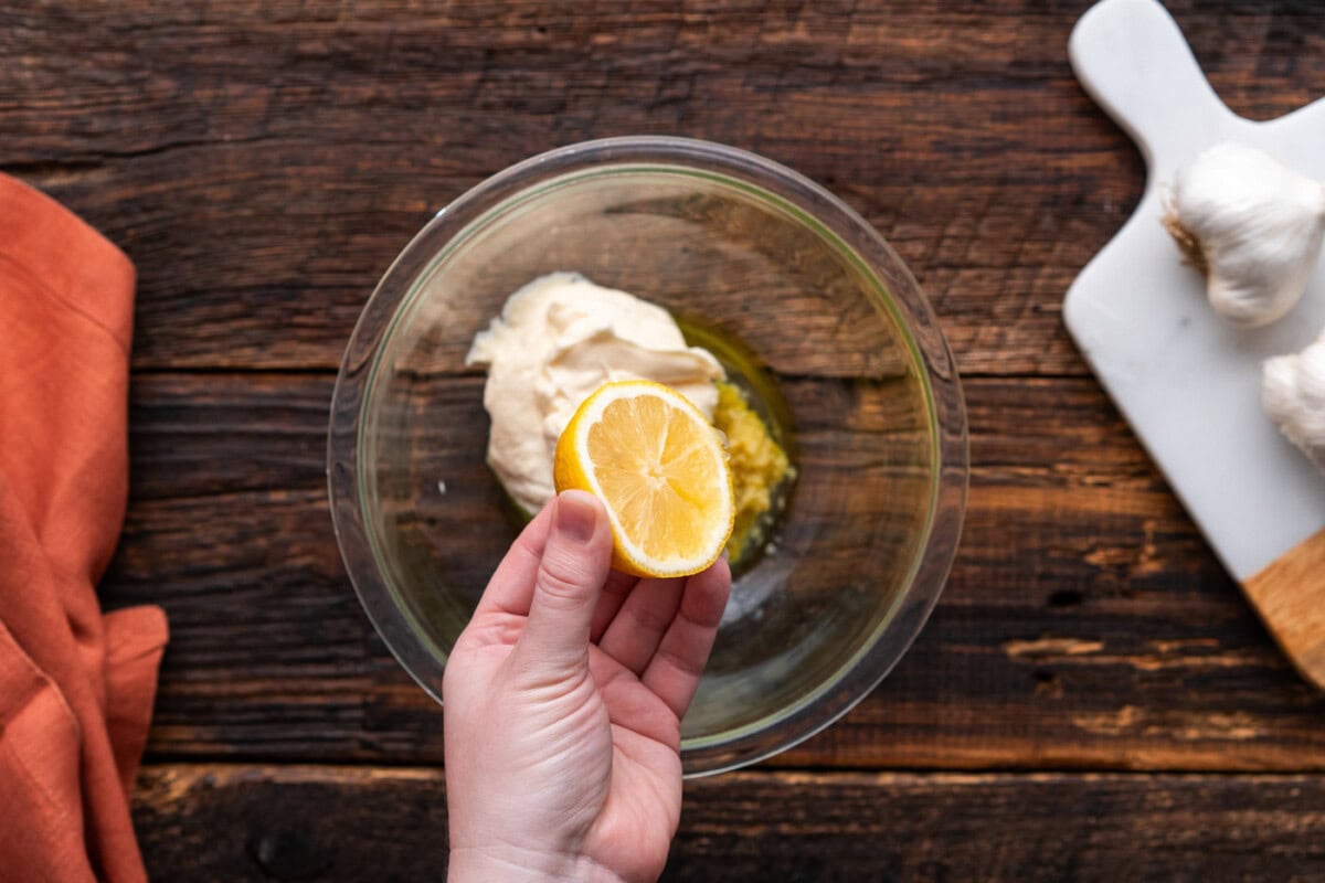 squeezing lemon juice into bowl of wing sauce ingredients