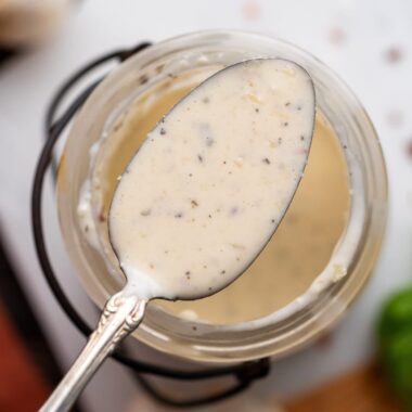 garlic parmesan wing sauce in a spoon over a jar