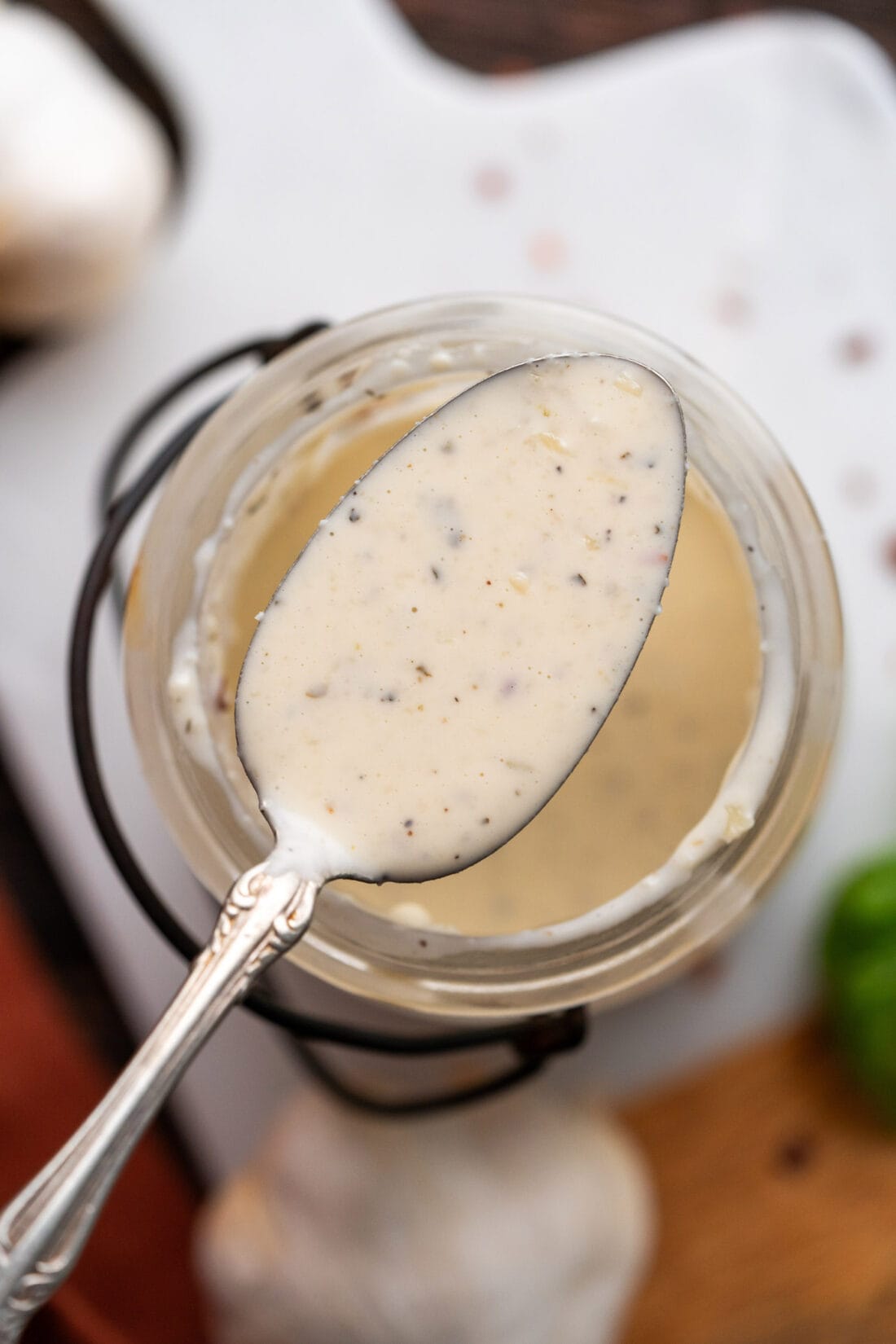 Spoon of Garlic Parmesan Wing Sauce held above a jar of sauce