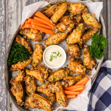 Serving tray of Garlic Parmesan Wings with a bowl of dipping sauce in the center