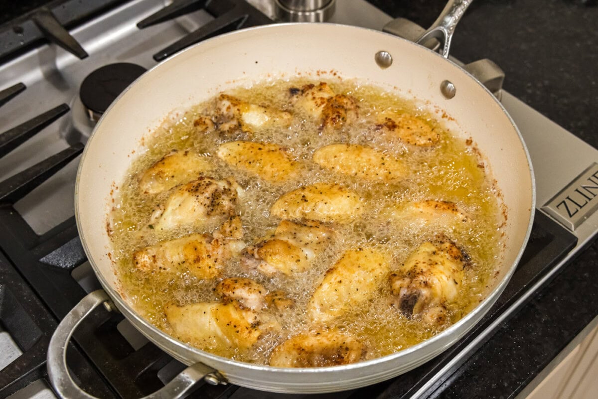 frying chicken wings in a skillet of oil