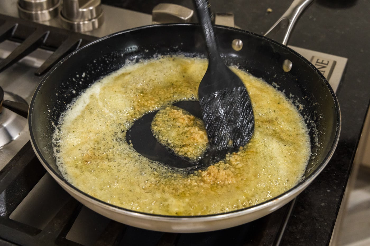 stirring minced garlic into seasoned butter ina skillet
