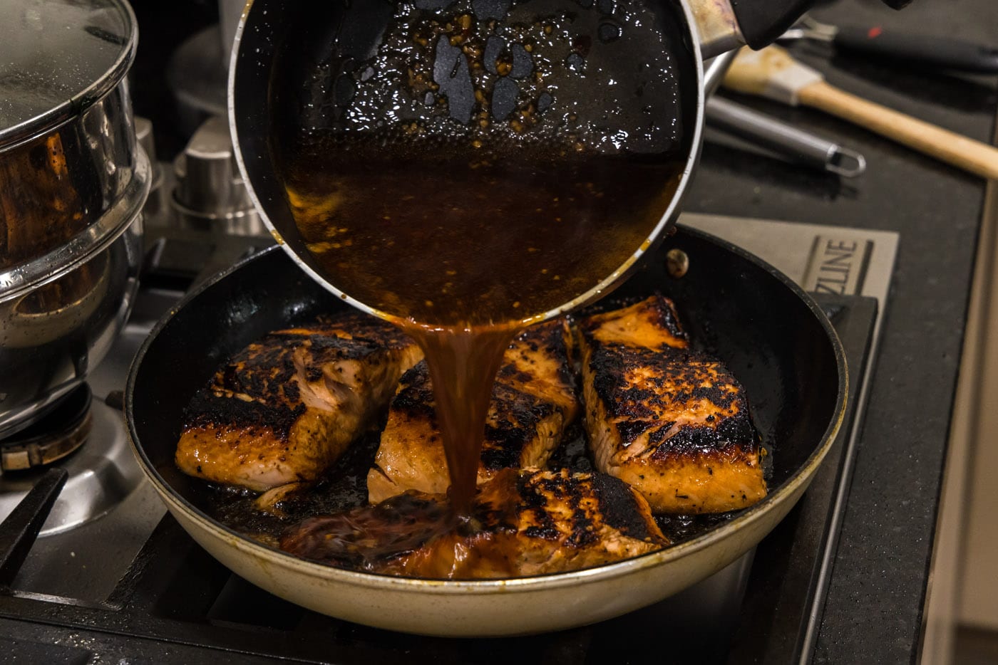 pouring honey glaze over salmon filets in a skillet