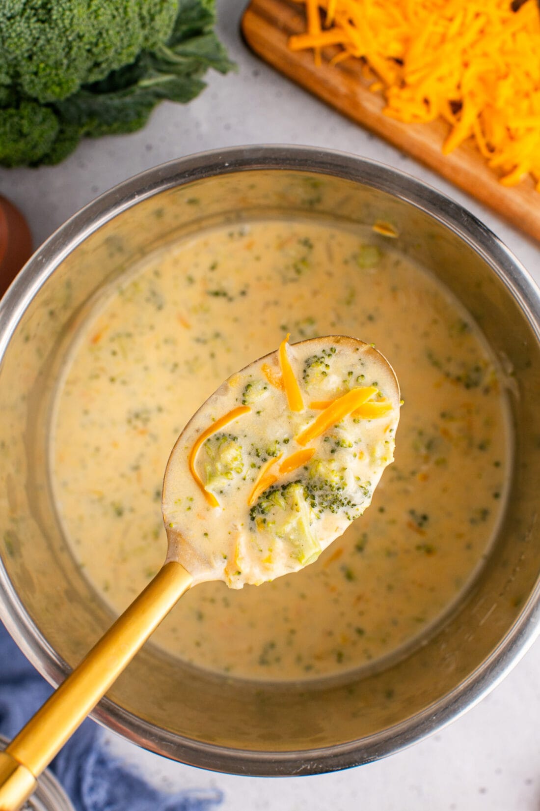 Spoonful of Instant Pot Broccoli Cheddar Soup being lifted above the instant pot