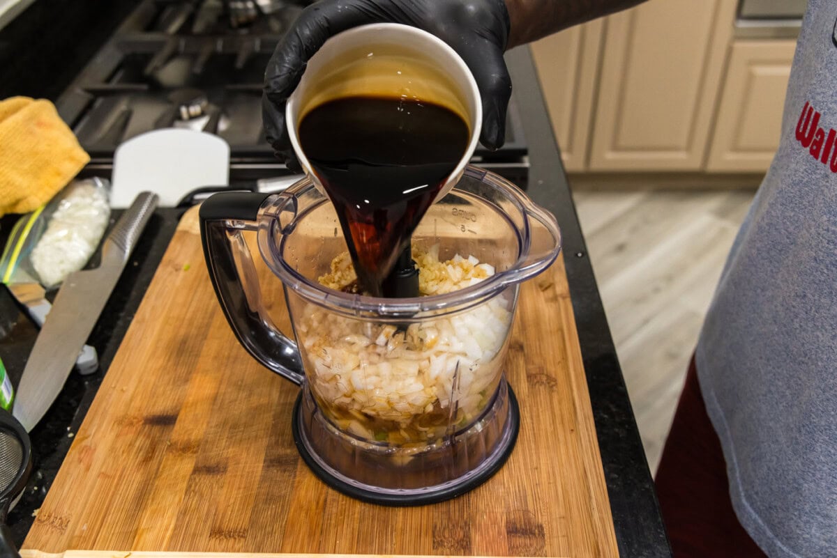 pouring soy sauce into food processor with Korean marinade ingredients