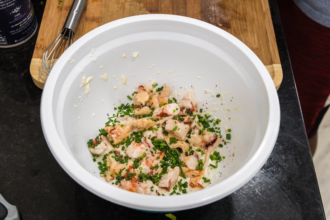 chopped chives added to cooked lobster meat and dressing in a bowl