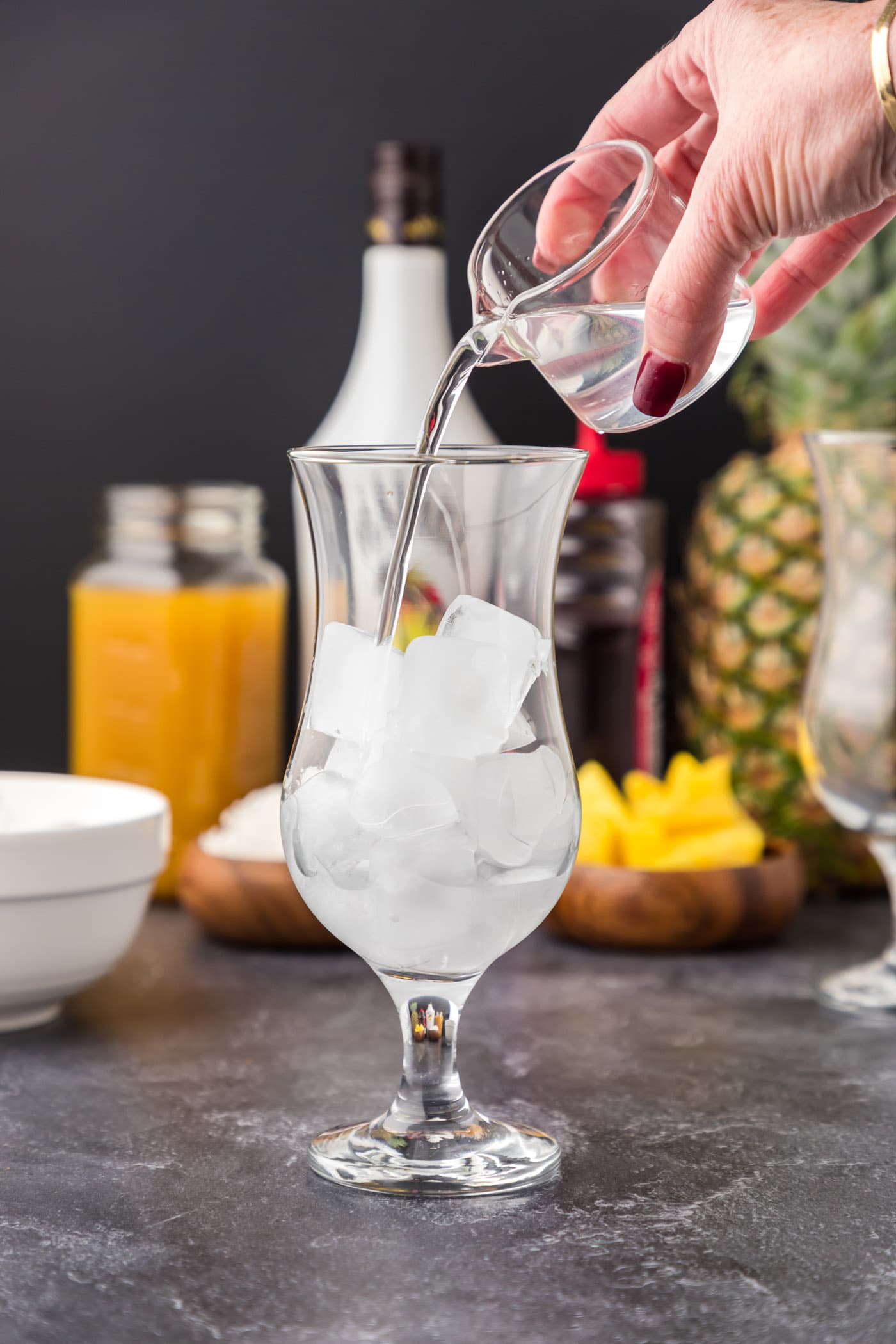 pouring coconut rum into glass of ice
