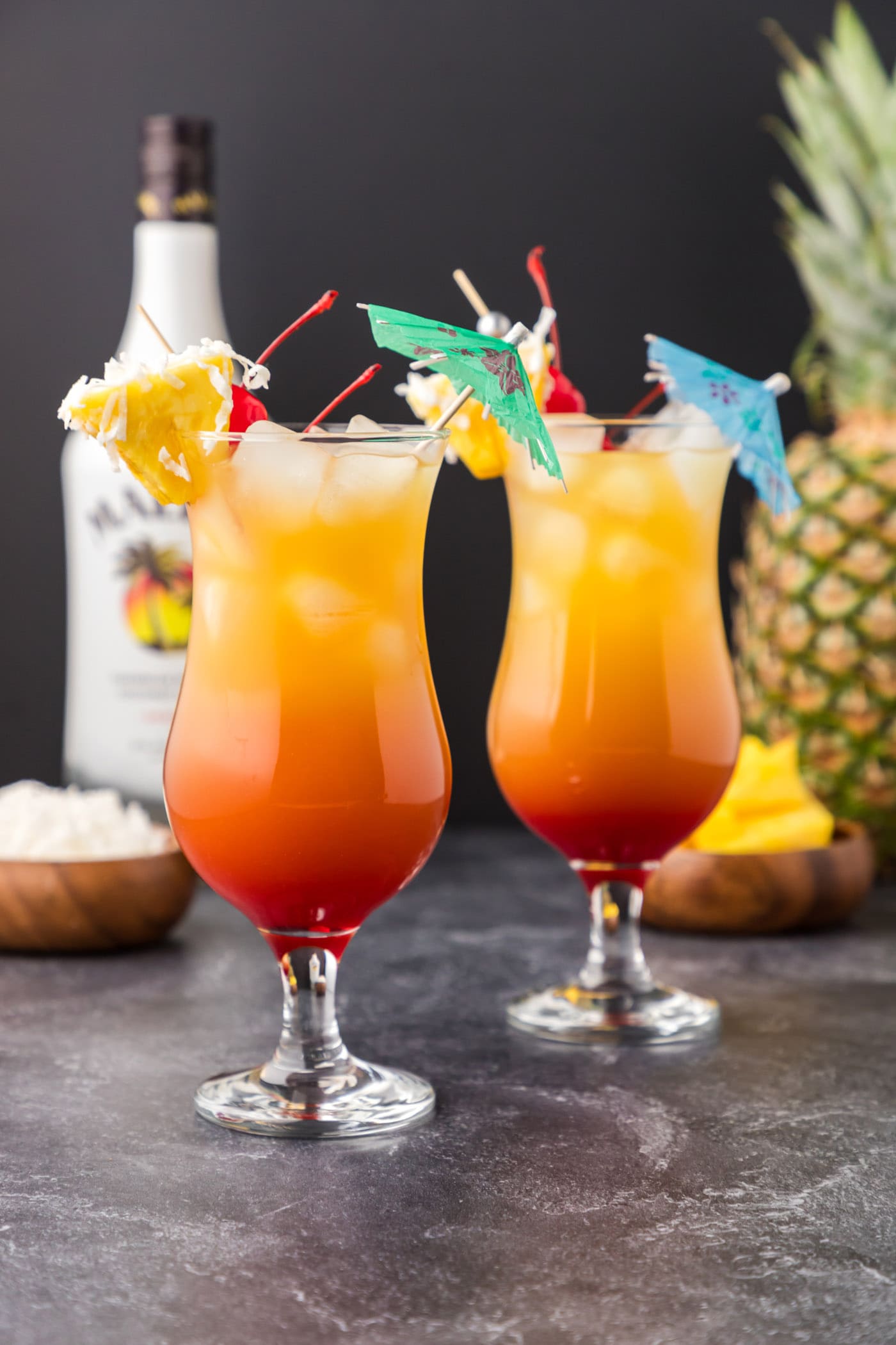 Malibu sunset cocktails with pineapple wedge and shredded coconut garnish