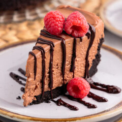 Slice of No Bake Chocolate Cheesecake on a plate drizzled with chocolate ganache