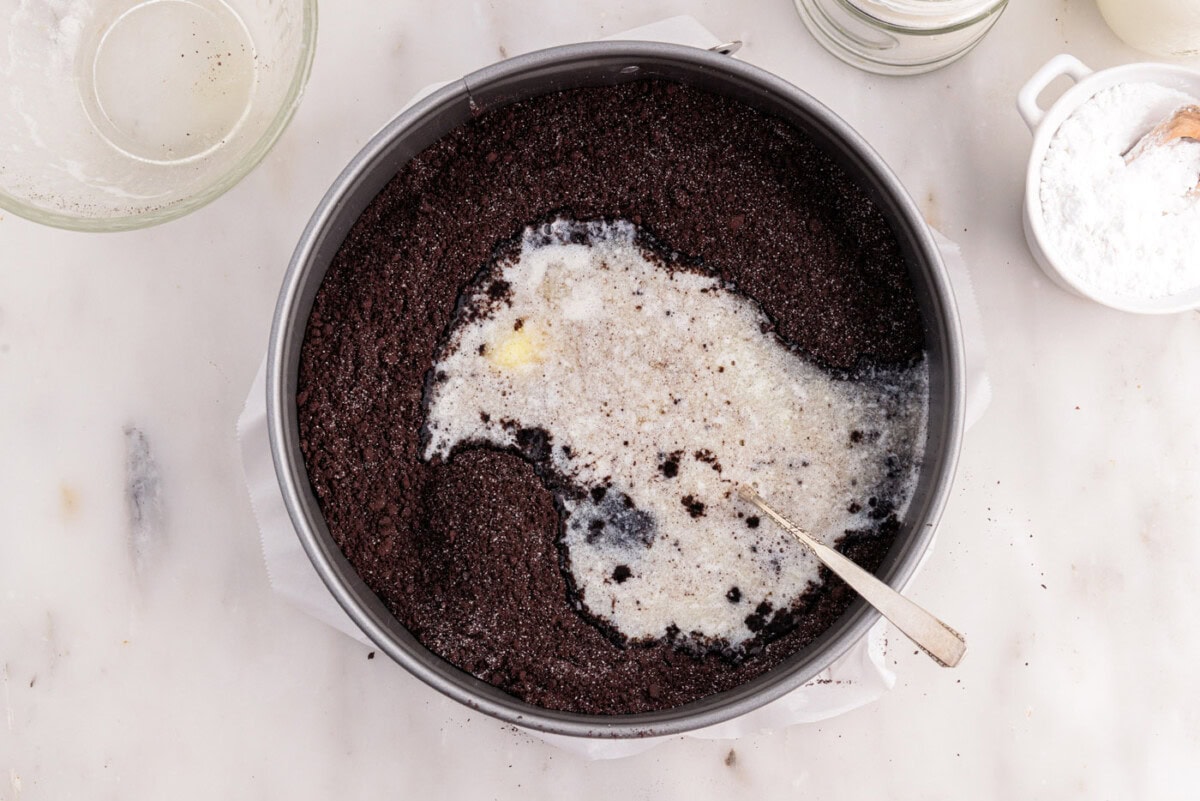 mixing graham cracker crumbs with melted butter into a sandy mixture