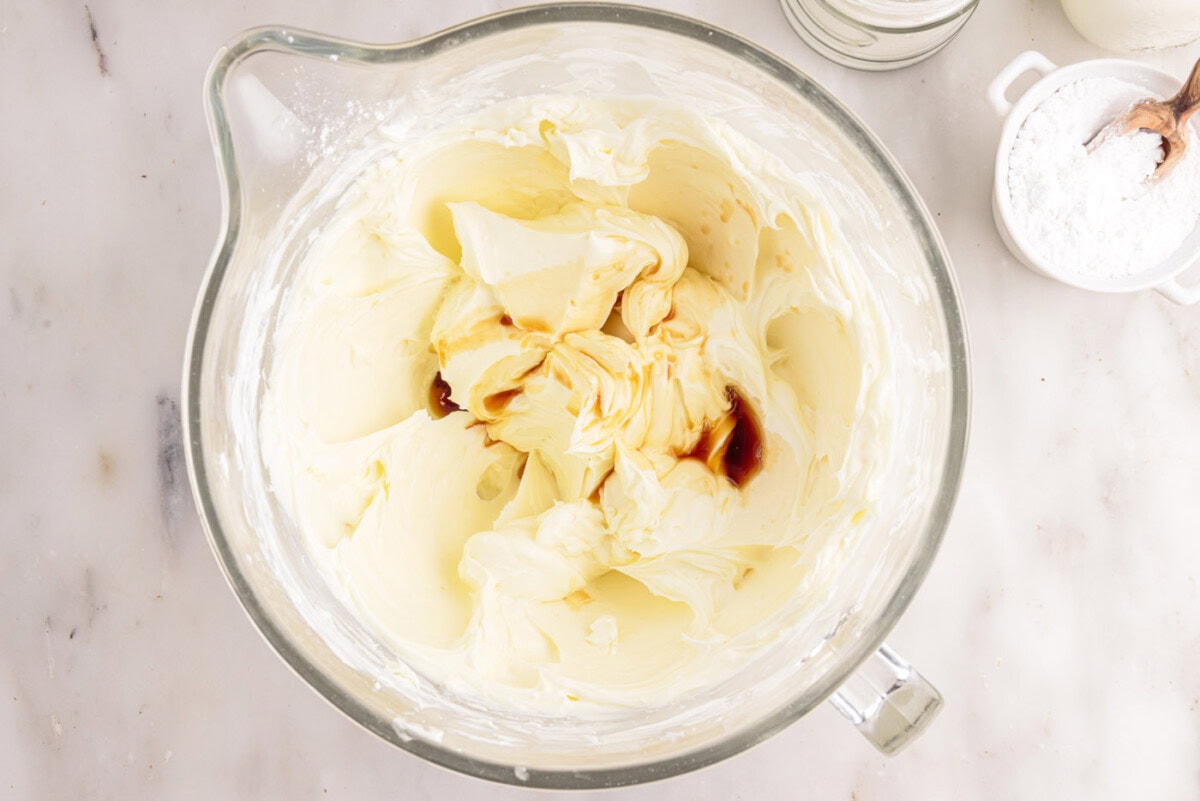 adding vanilla to cream cheese mixture in a bowl