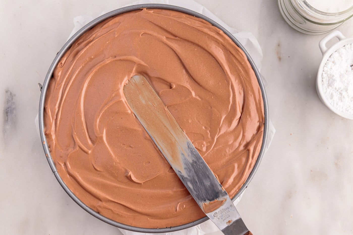 smoothing no bake chocolate cheesecake mixture in a springform pan