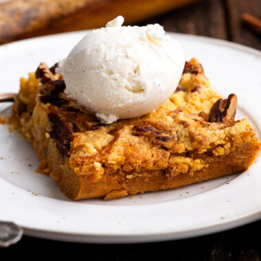 Close up photo of a piece of Pumpkin Dump Cake topped with ice cream