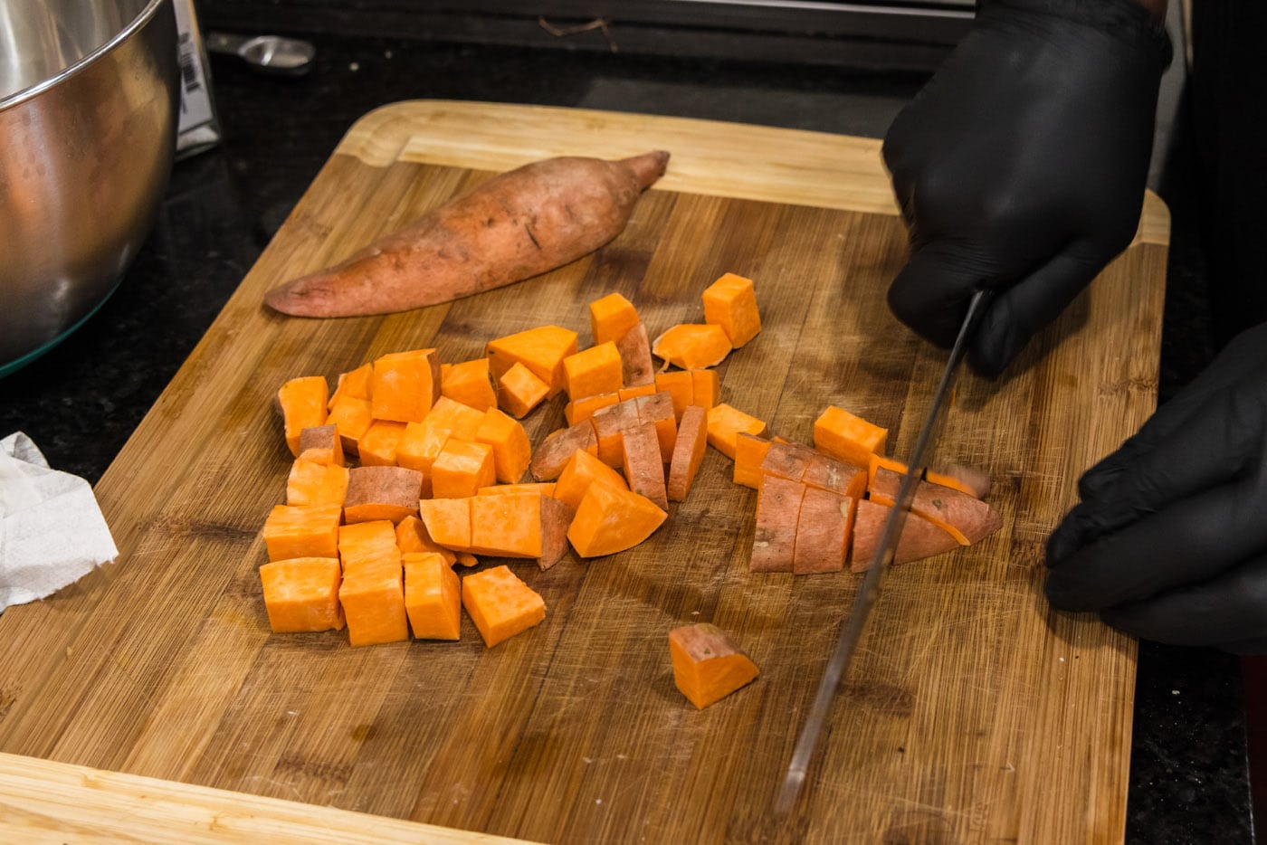 dicing sweet potatoes with a knife on a cutting board