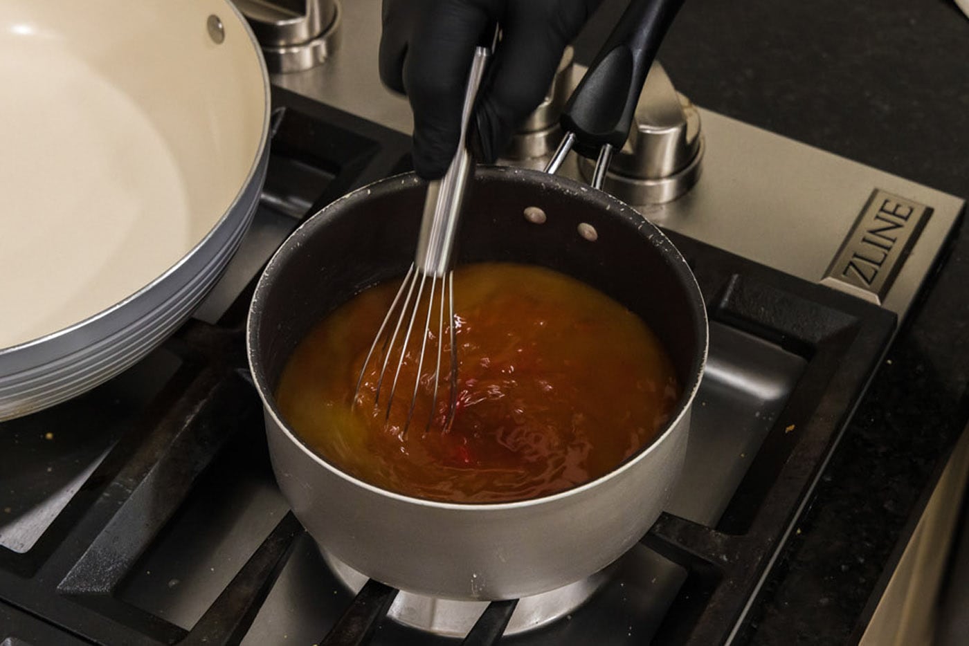 sweet and sour sauce ingredients being whisked in a saucepan