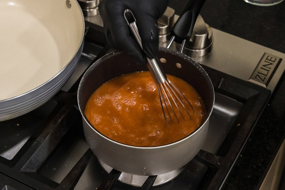 whisking sweet and sour sauce in a saucepan