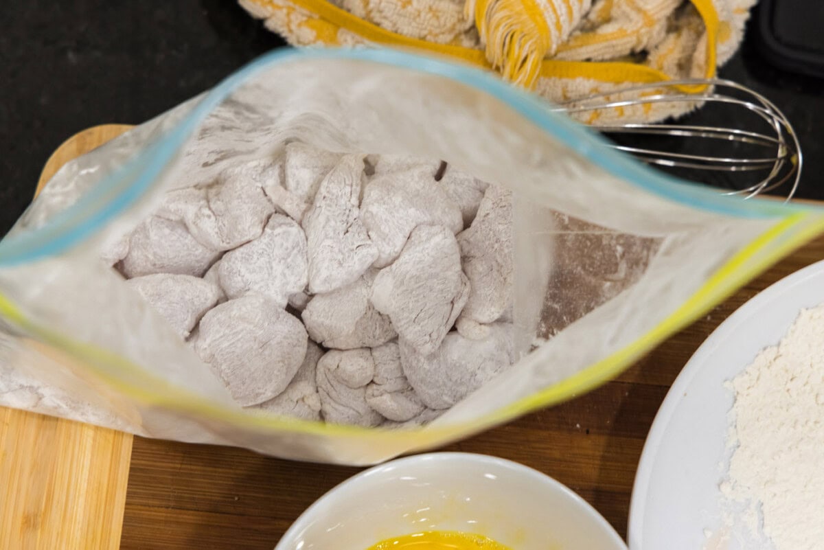 cubed chicken coated in cornstarch in a bag