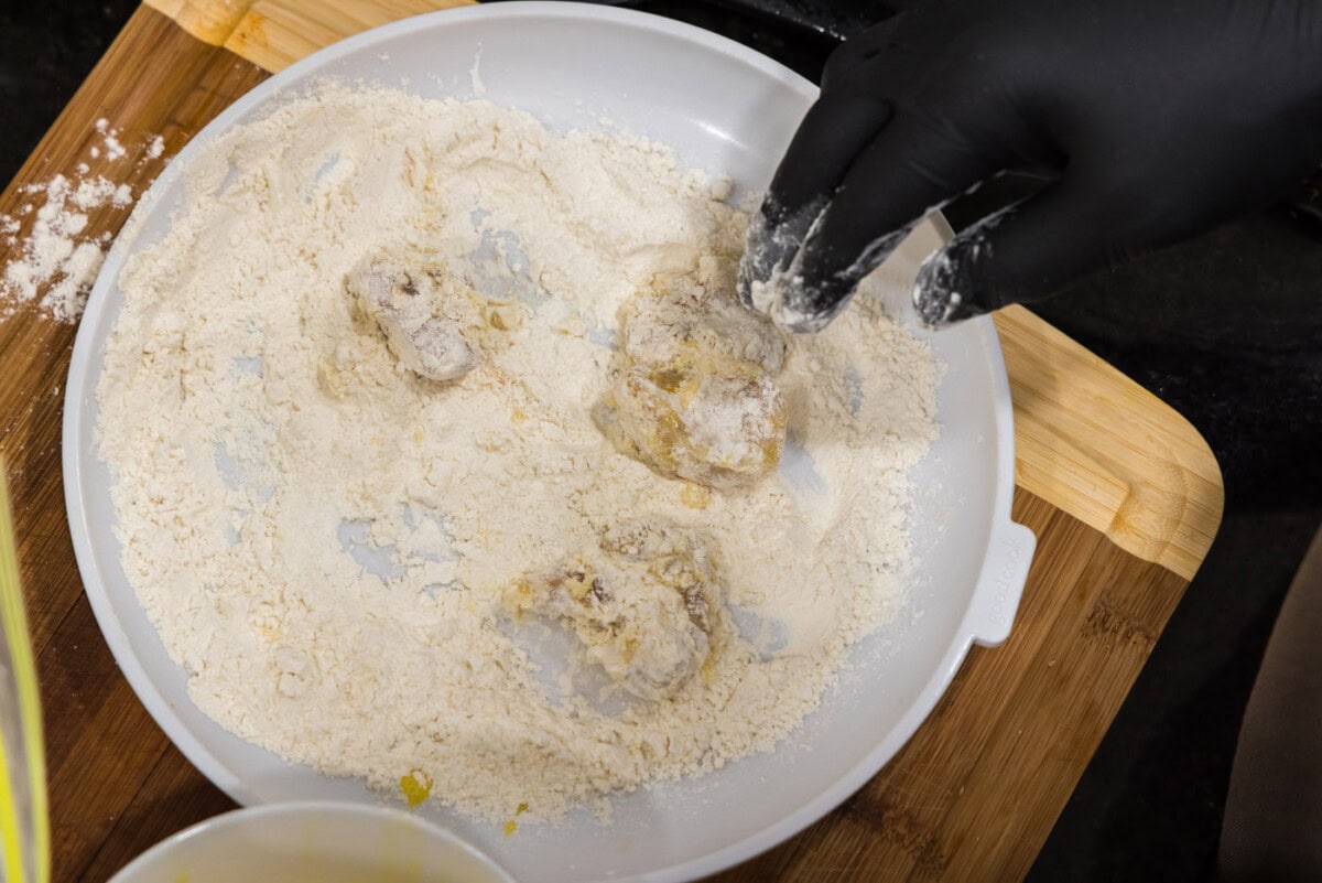 tossing dredged chicken cubes in flour
