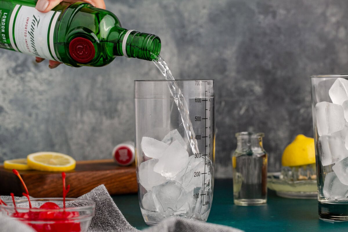 pouring gin into cocktail shaker with ice