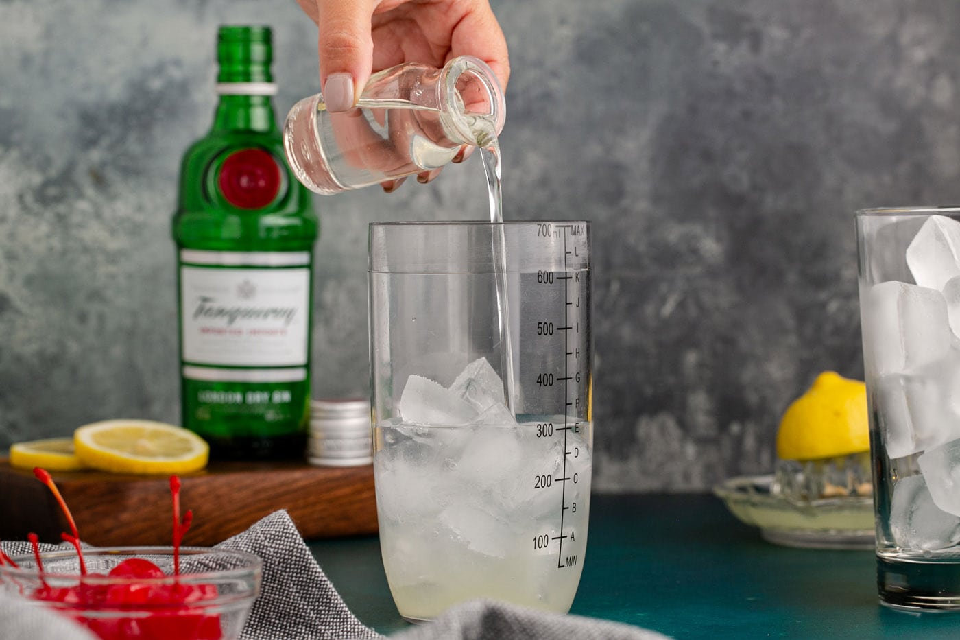 pouring simple syrup over gin and lemon juice