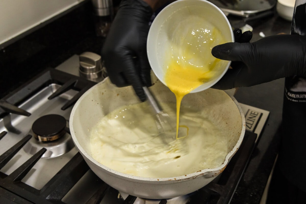 tempering eggs in heavy cream in a skillet