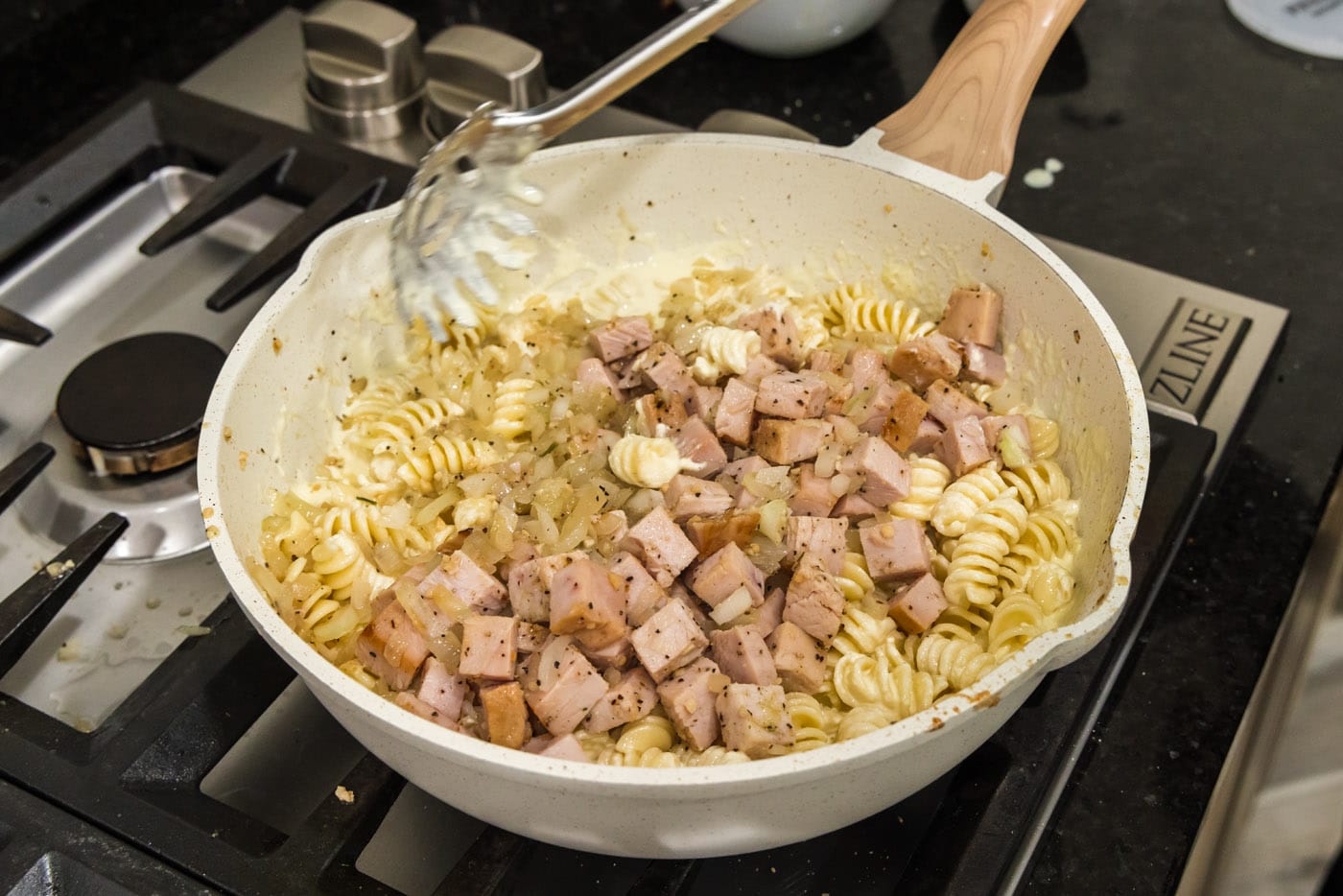 cubed turkey and onion mixture added to skillet with pasta and carbonara sauce