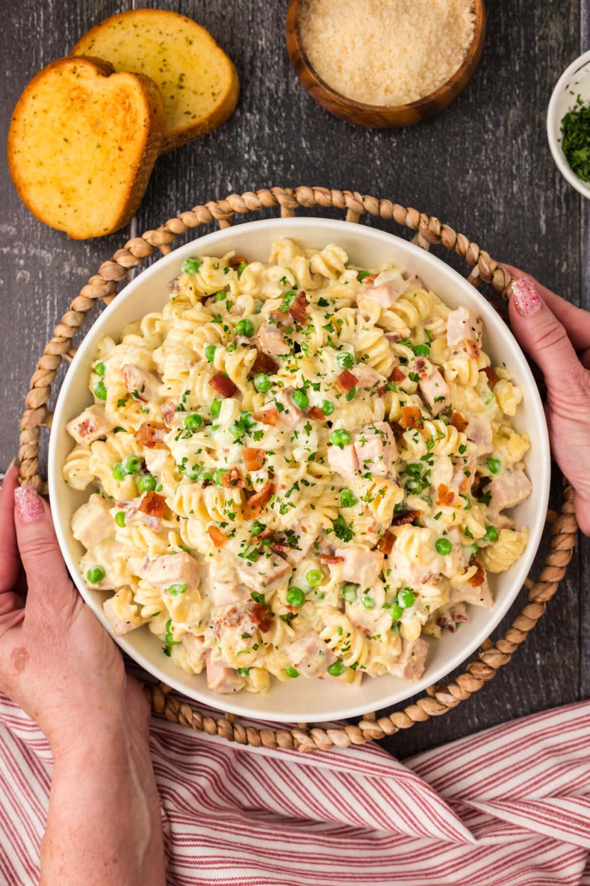 Hands holding a serving bowl of Turkey Carbonara