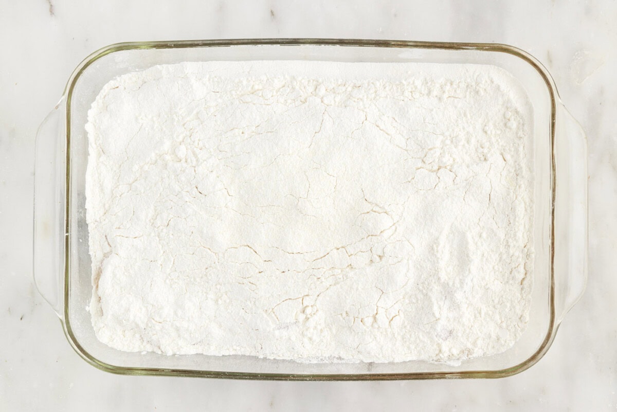 dry cake mix spread over apple pie filling in a baking dish