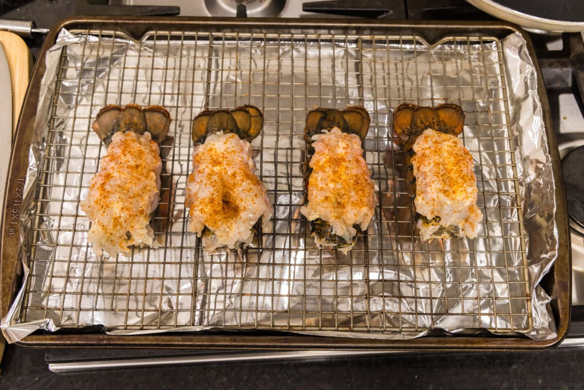 Old bay seasoned crowned lobster tails on a baking sheet