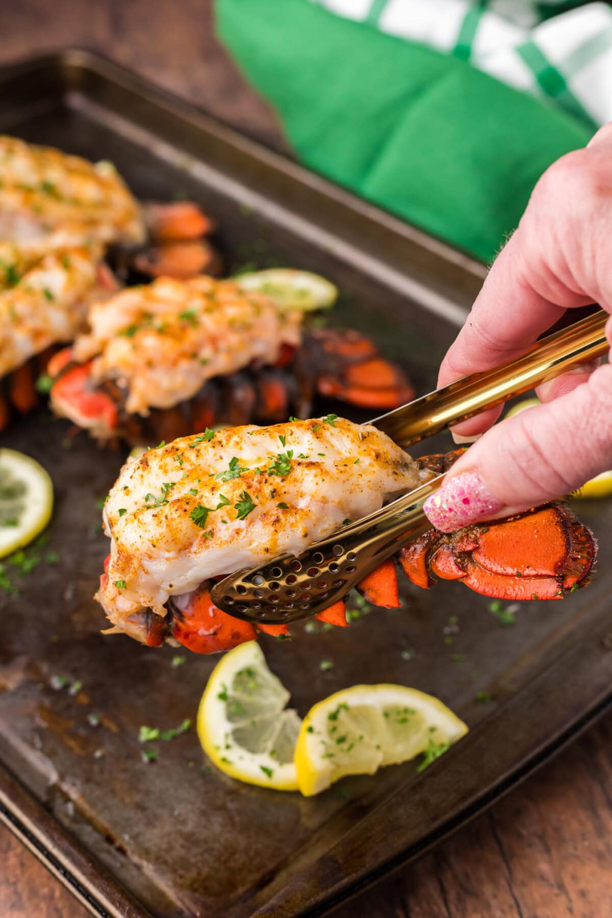 Tongs lifting up a Baked Lobster Tail
