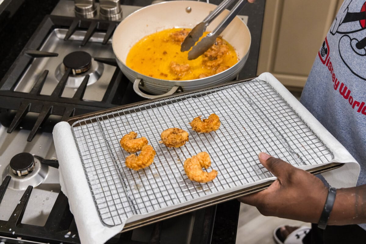 tongs removing fried shrimp from oil