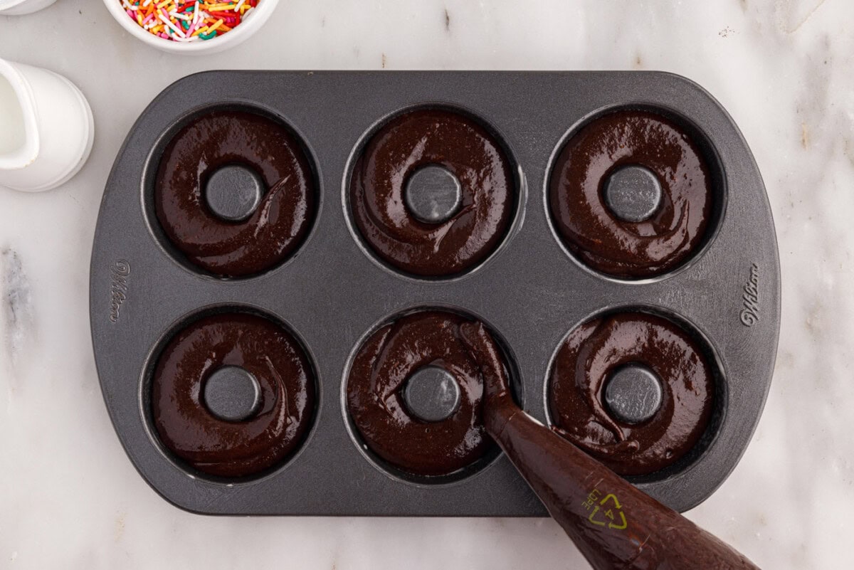 piping bronut batter into donut pan