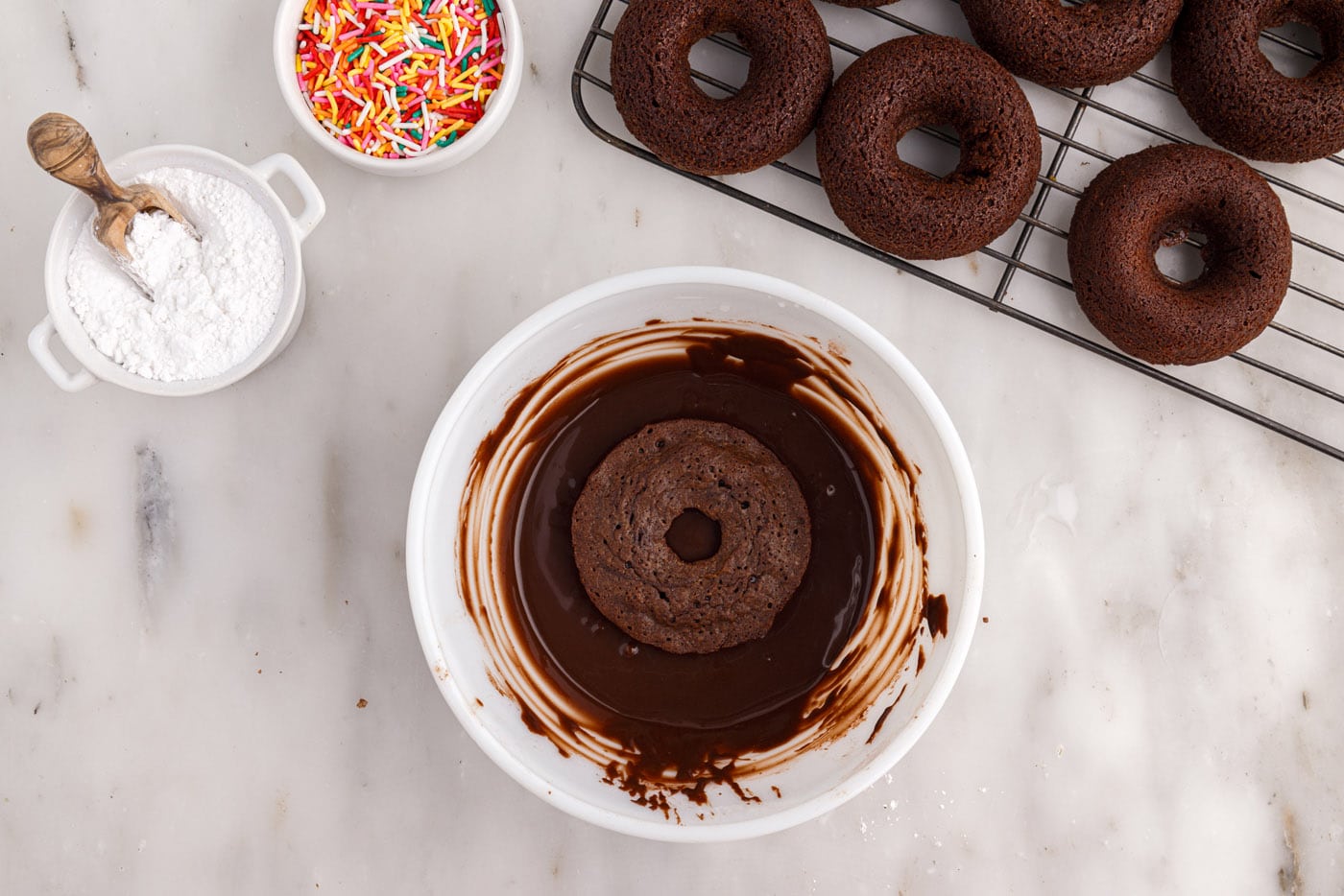 dipping a donut into chocolate glaze