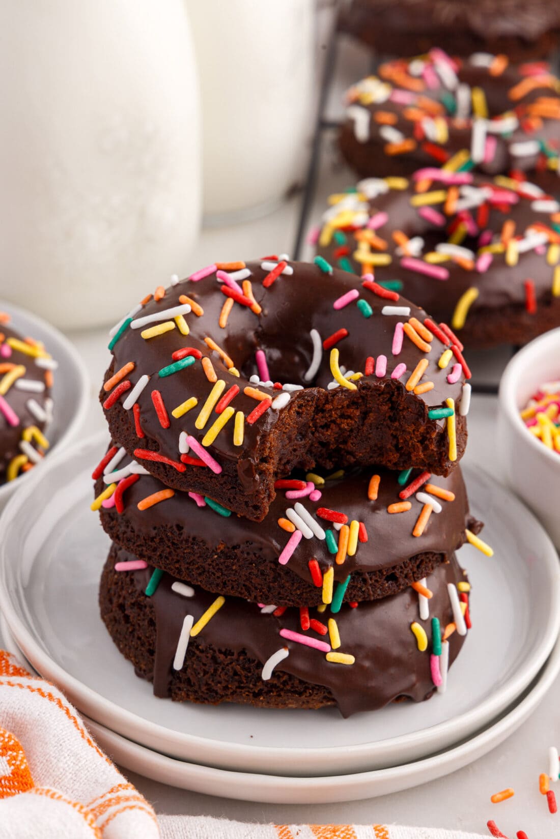 Stack of Bronuts topped with rainbow sprinkles with a bite taken out of the top one