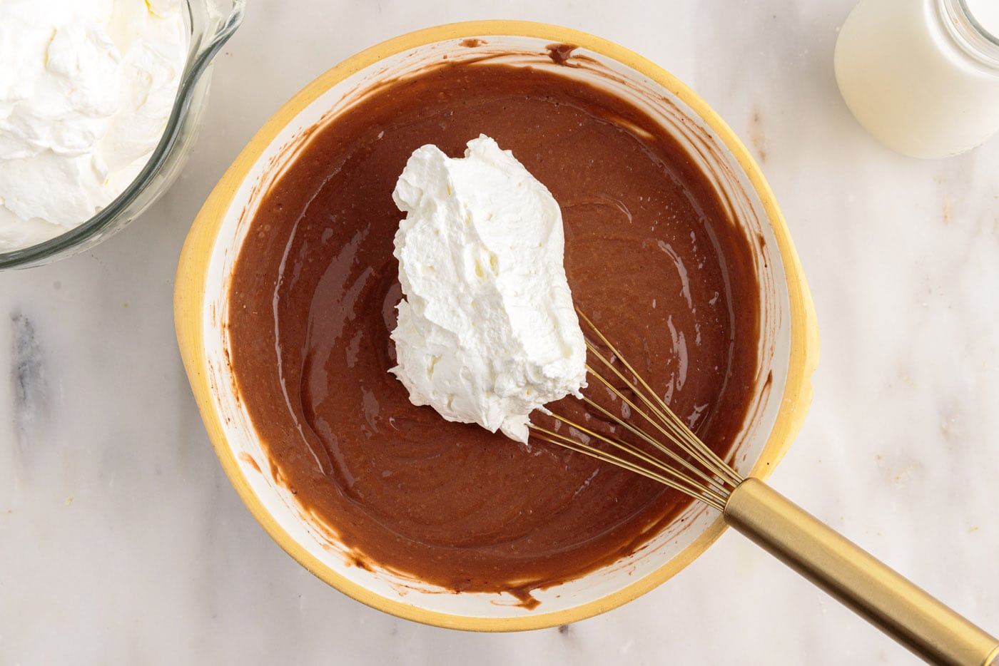 adding whipped cream to chocolate pudding in a bowl