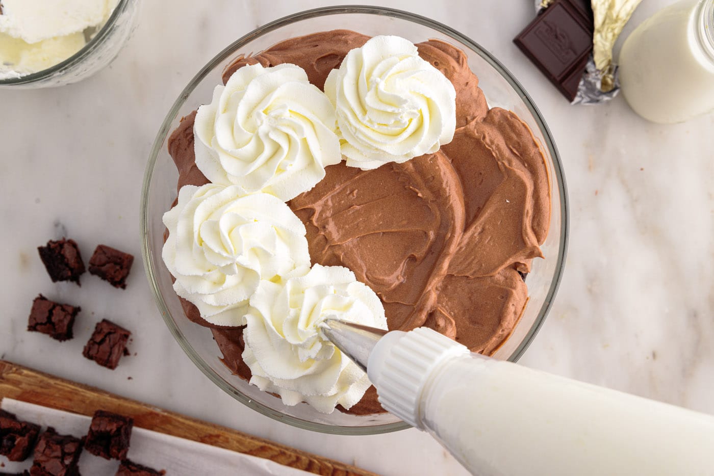 piping whipped cream on top of brownie trifle