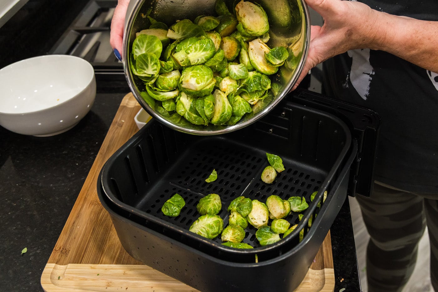 adding brussels sprouts to an air fryer basket