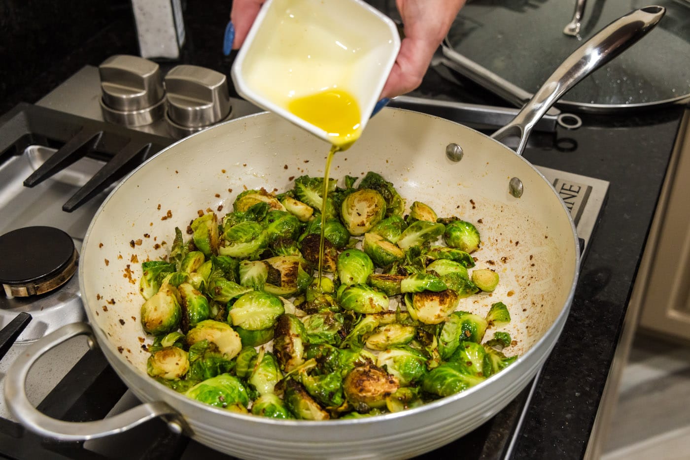 pouring oil into brussels sprouts in a skillet