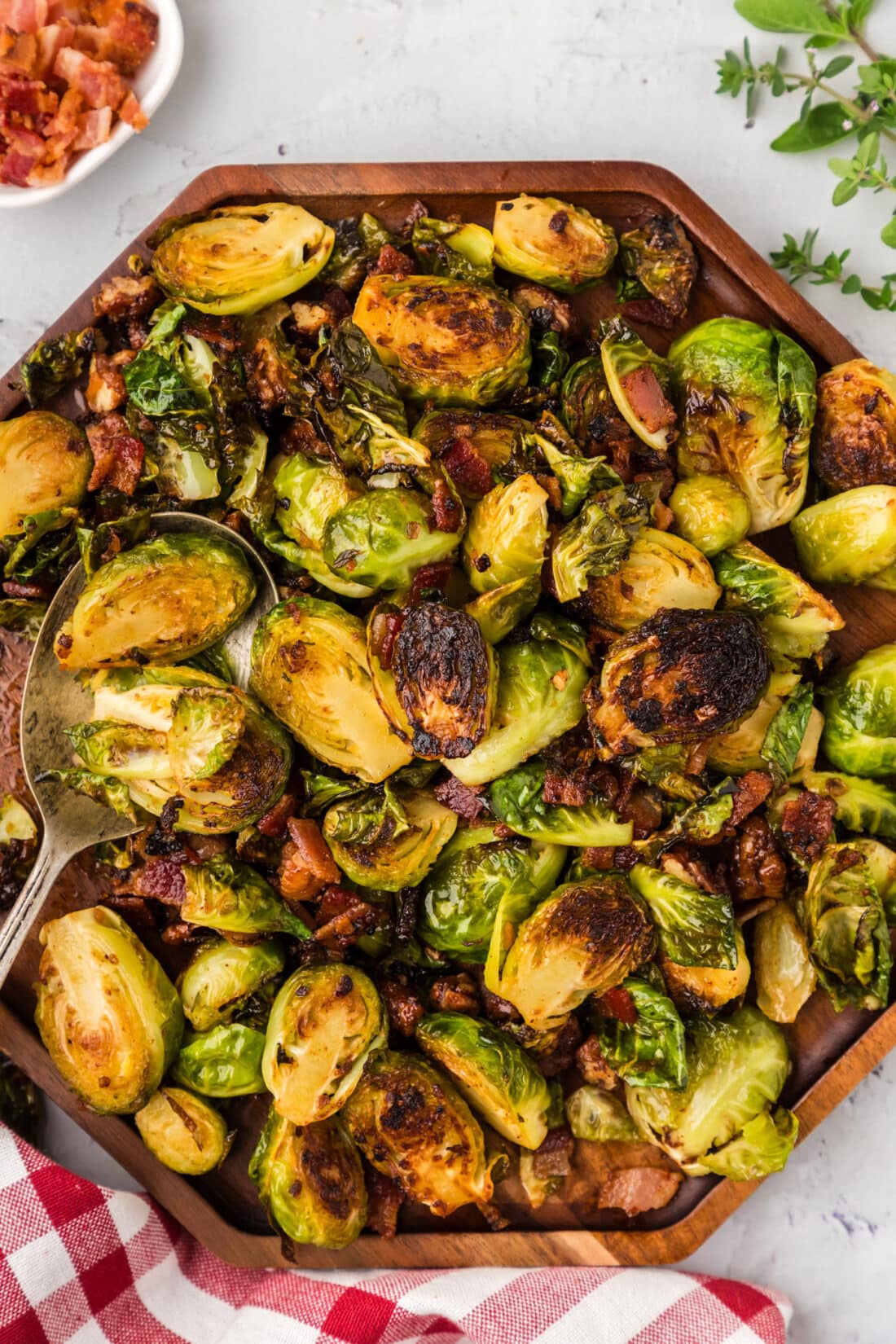 Close up photo of Brussels Sprouts with Bacon, Shallots and Candied Pecans on a wooden platter