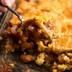 Close up photo of a spoonful of Caramel Apple Dump Cake being lifted out of the pan